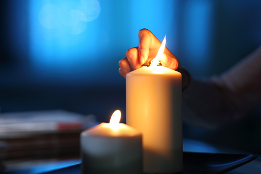Woman hand lighting candle in the night at home