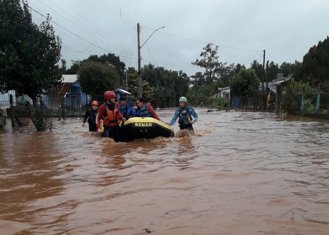 Moradores sendo removidos de área inundada em Riozinho (Foto: Bombeiros Voluntários)